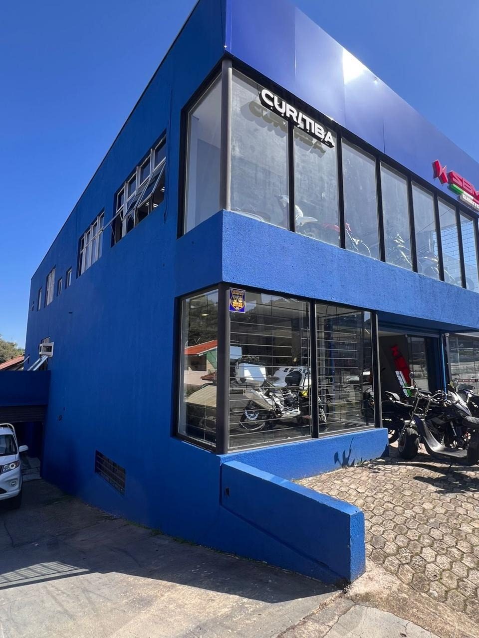 Fachada azul da SBM Curitiba, com o letreiro Curitiba e motocicletas expostas na vitrine